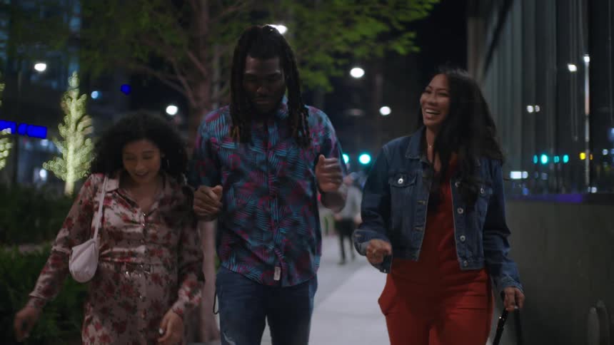 Friends laugh while walking and talking at night