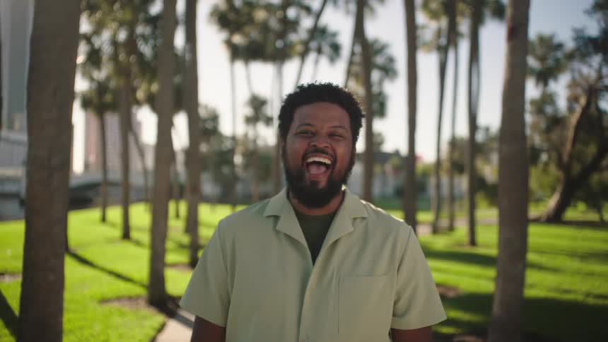 A man is laughing by the trees