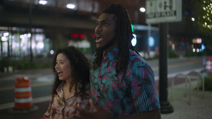 Woman and man embracing walking down a city sidewalk at night