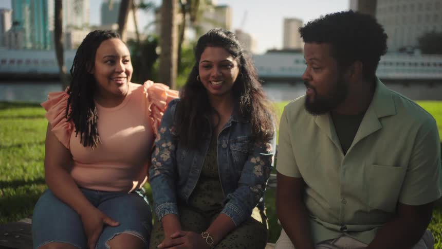 Man and two women sitting in a square talking