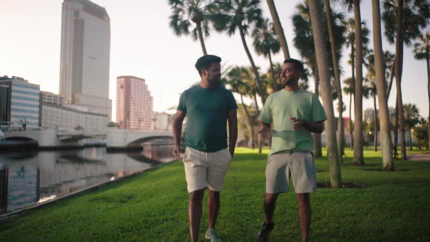 Two men walking on the grass in a park talking