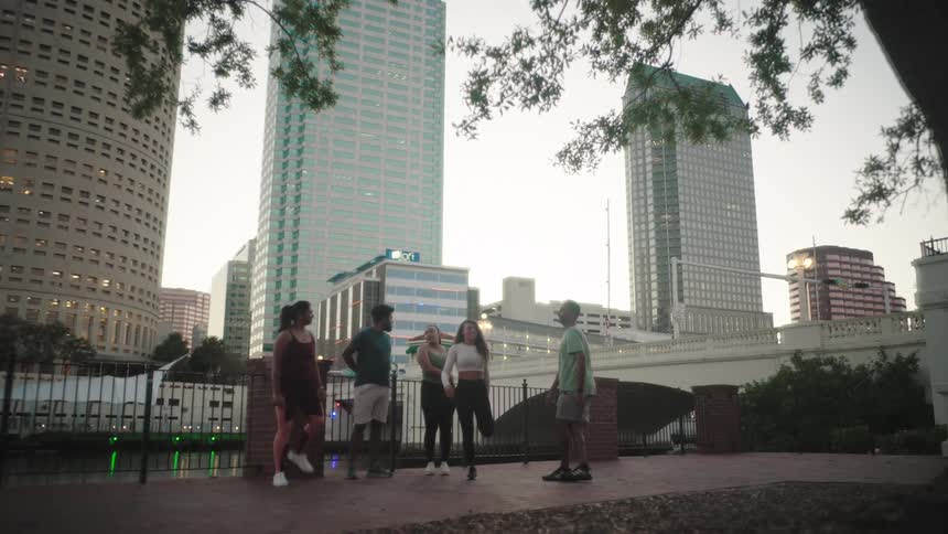 People in a workout group stretch while in a park across the river from downtown near dusk