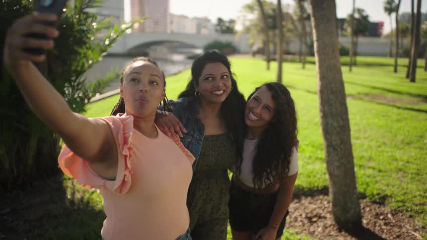Three girlfriends pose for a selfie with the city behind them