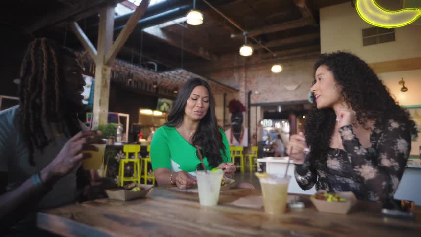 Three friends talking and drinking at a restaurant table