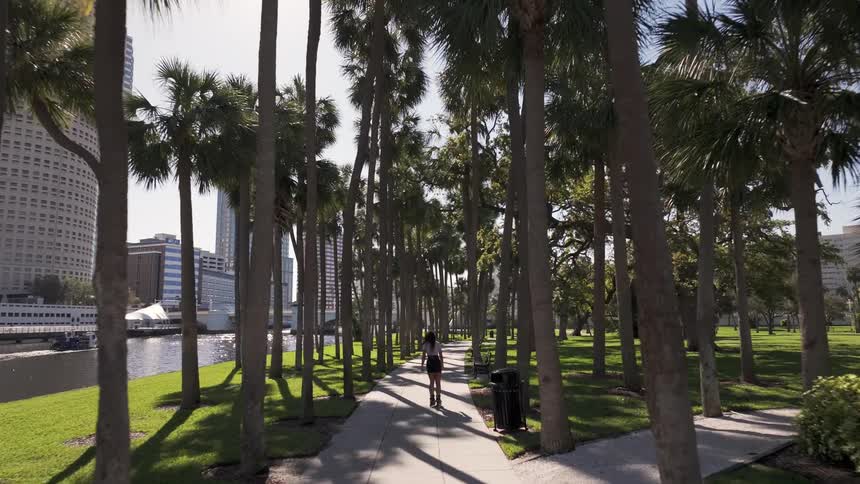 A woman roller skates on a city park sidewalk on a sunny summer day