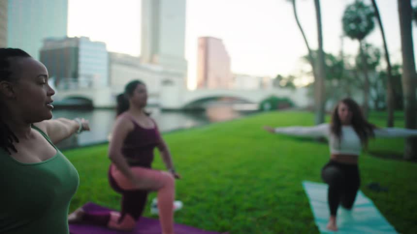 A group of women are exercising on mats in a city park