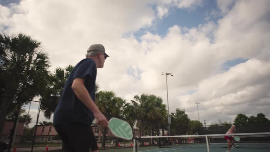 A man hits the pickleball with his racket