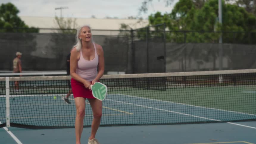 A woman serves the pickleball during a match