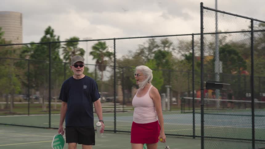 A man and woman talk while walking on the court