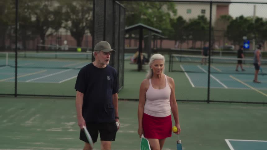 Elderly couple leaving an outdoor tennis court
