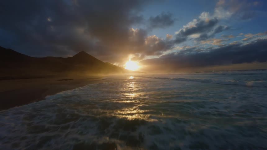 Waves crash along the coast at sunset