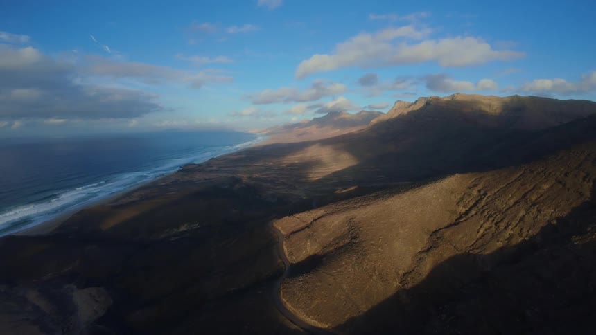 Flying over a mountain range by the ocean