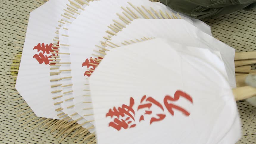 A stack of hand fans with chinese characters lay on the floor