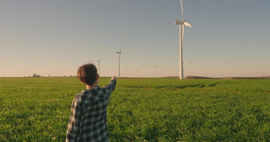 A footage of a boy pointing at a wind turbine