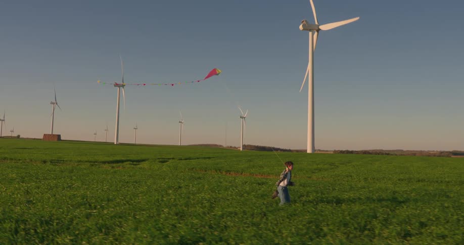 Boy running through a farm field playing with a kite