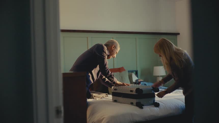 A footage of a man and a lady packing a luggage in a room