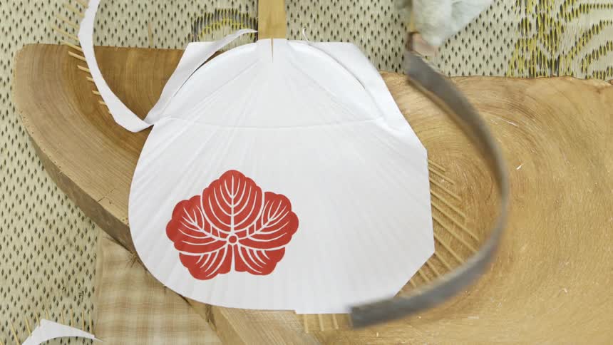 A person is using tools to form a paper fan