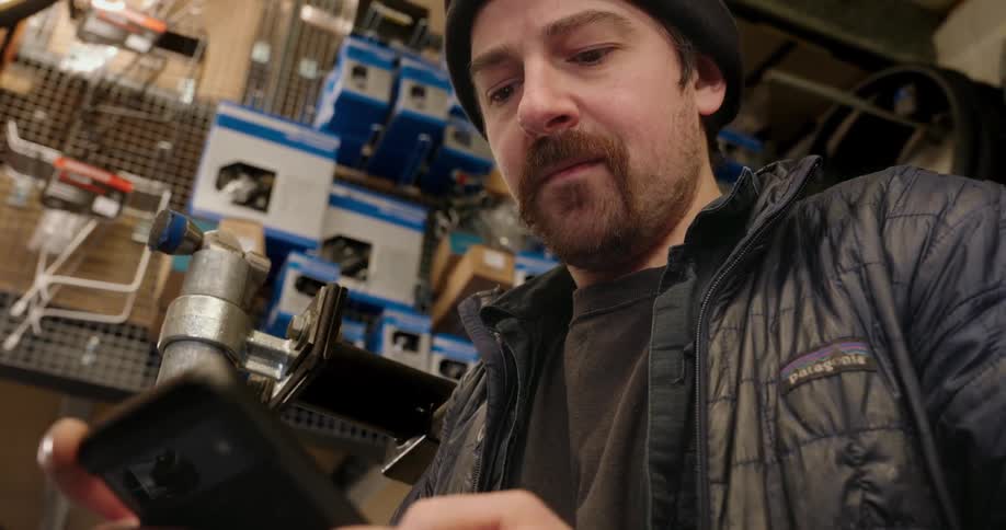 Man standing in a store scrolls on his smartphone
