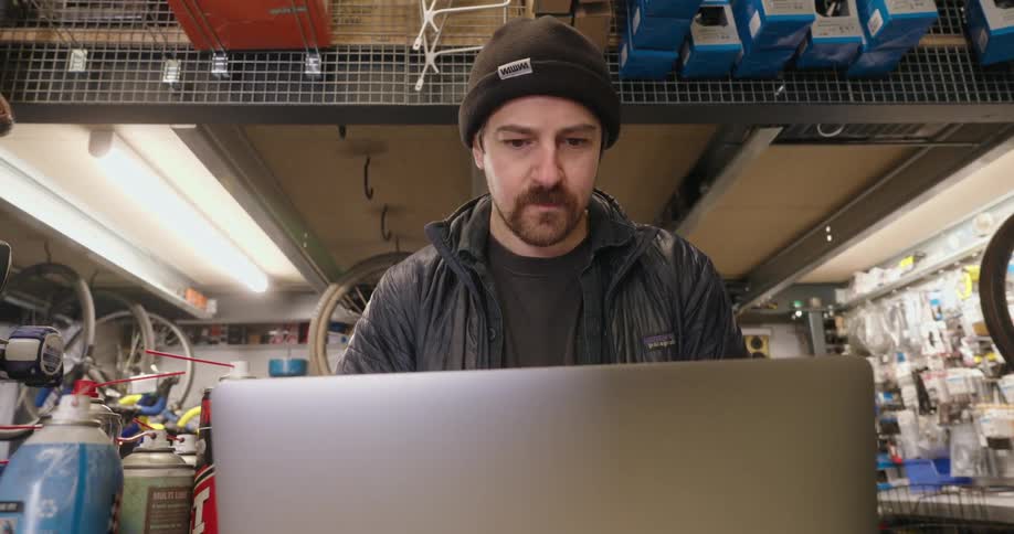 Man works on a computer while standing in a bicycle shop