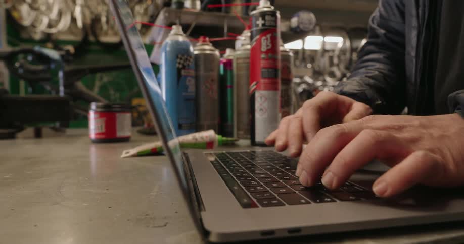 A man is typing on his keyboard by some spray cans