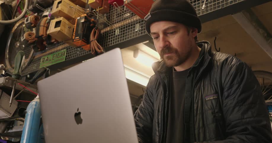 The worker types on his laptop in the bike shop