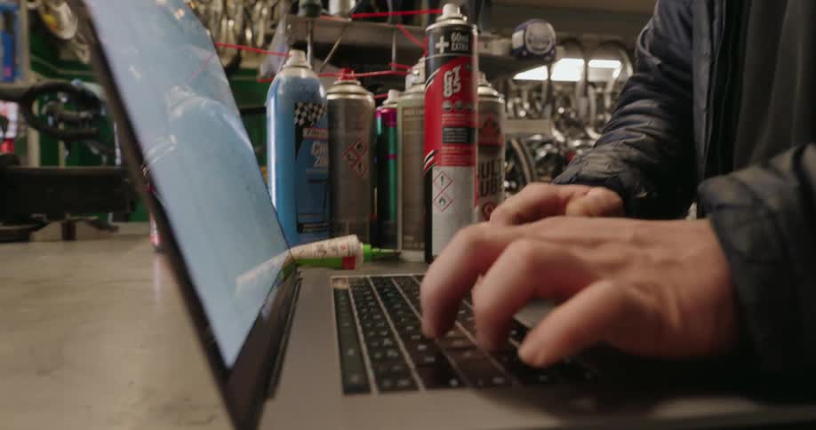 A worker is using a laptop in the bike shop