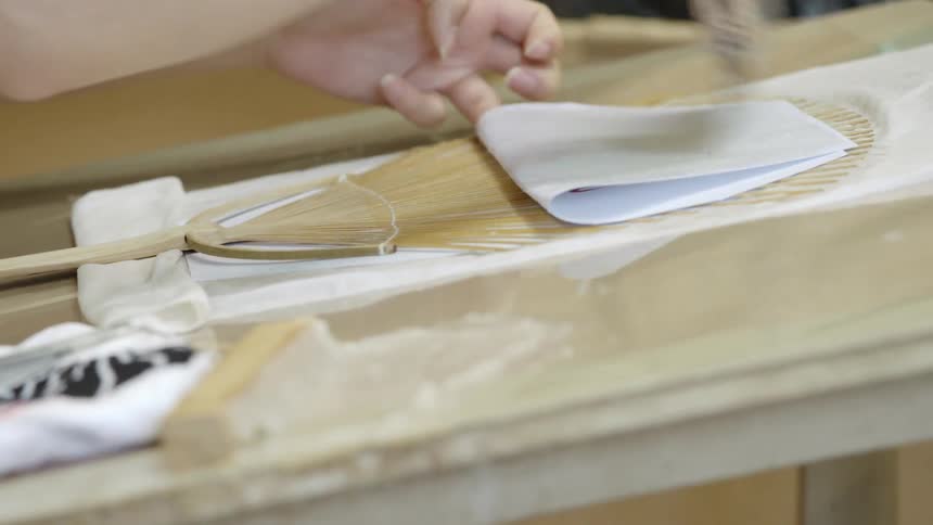 A person applies glue to a fan