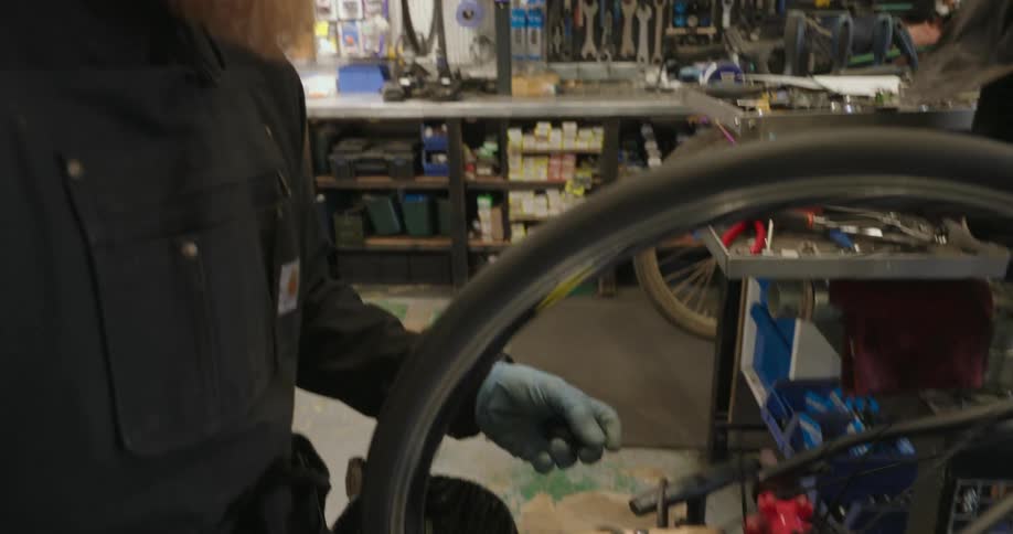 Man with gloves working on a bicycle frame in a mechanic workshop