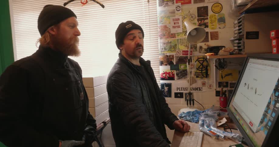 Two men talking and interacting with a computer screen