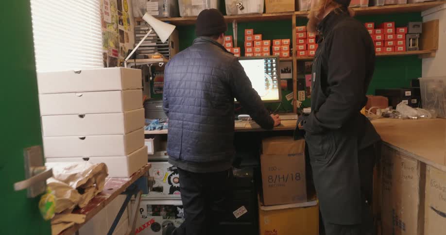 Two men interacting with a computer in a store