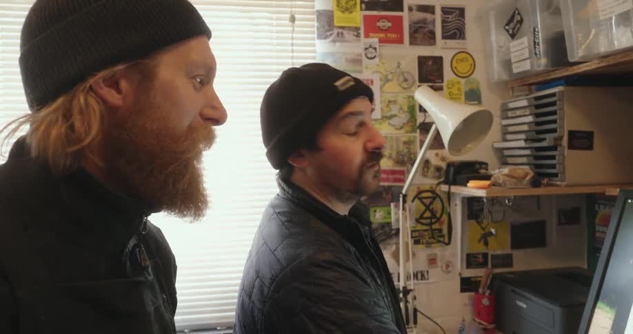 Two men are talking while looking at a monitor
