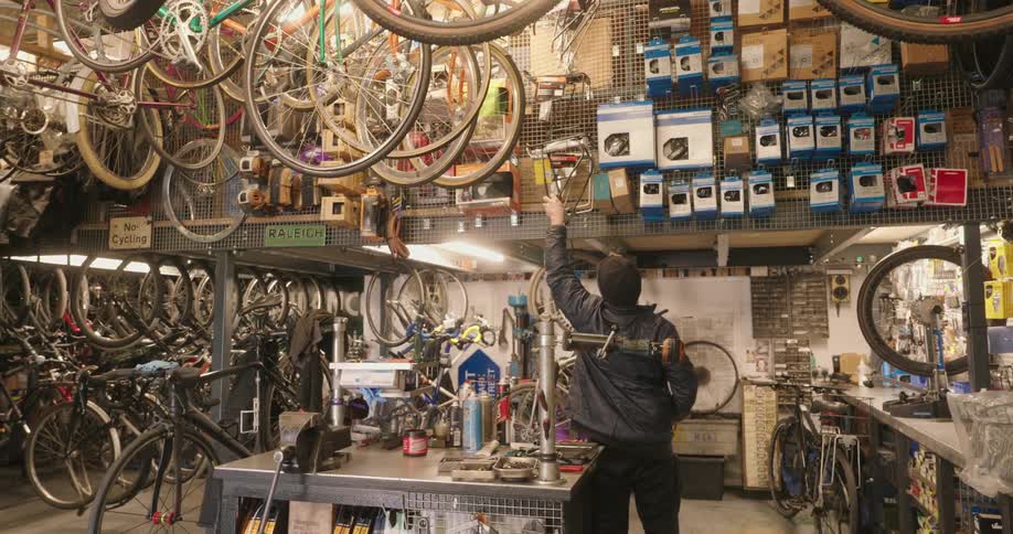 Man working in a bike shop puts merchandise out before carrying the emptied box away