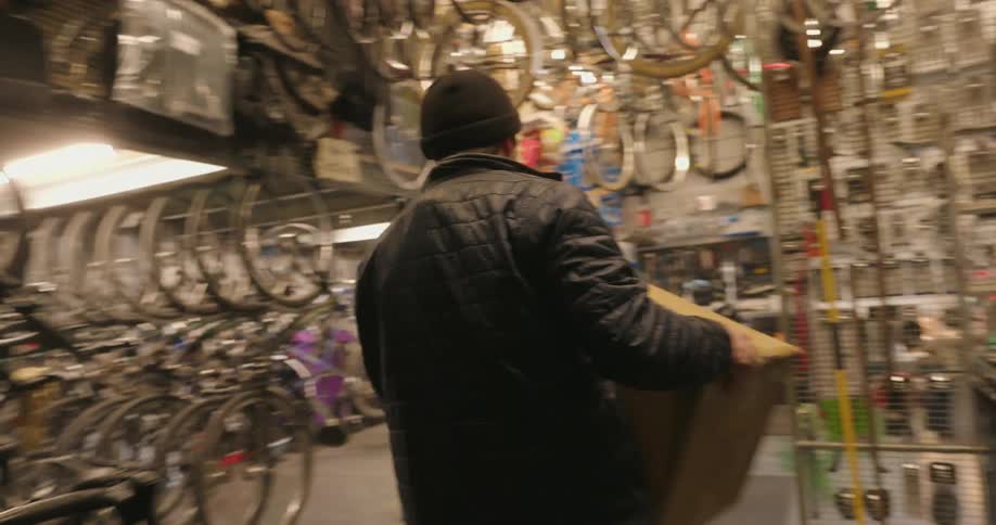 A man carries a carboard box down the steps in the store