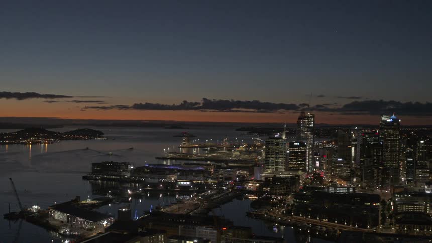 The illuminated cityscape of auckland at night features its prominent sky tower piercing the dark sky