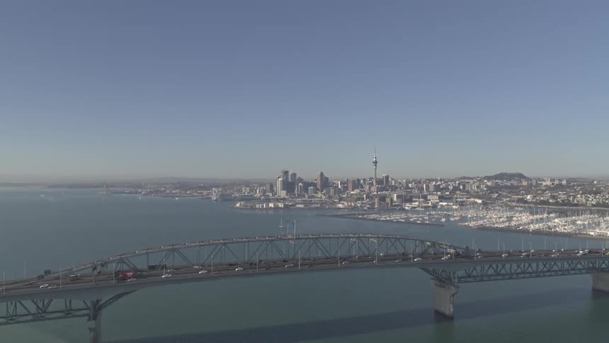 An aerial view shows the auckland harbour bridge under a clear sky