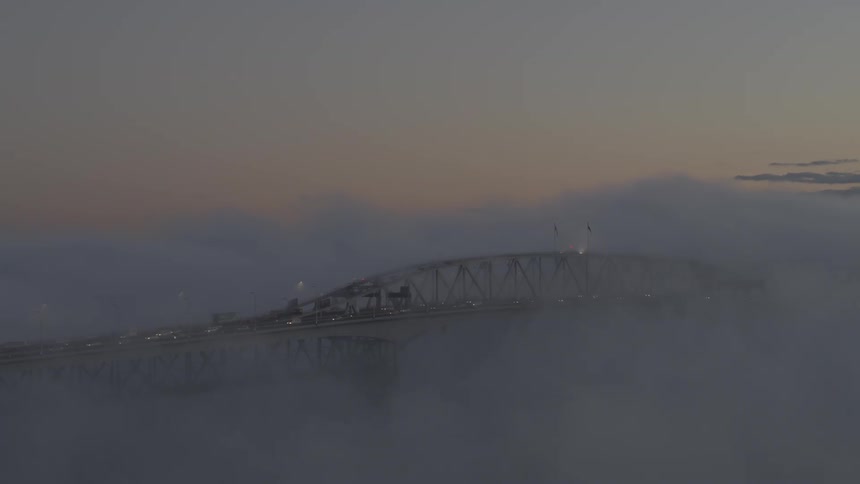 The bridge is covered with fog at sunrise