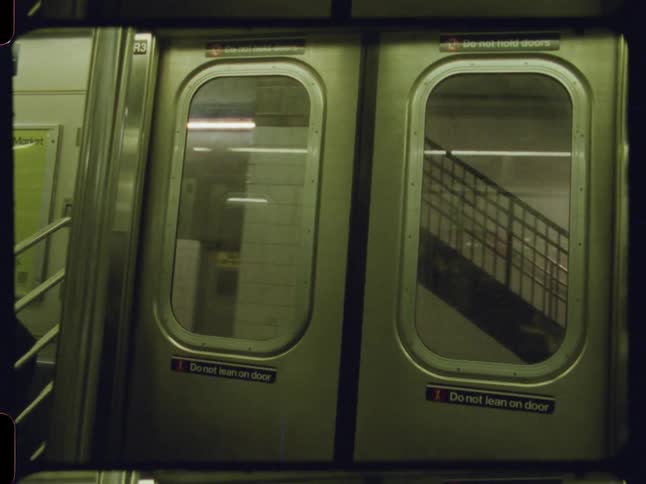 Interior view of a closed train door moving through a station
