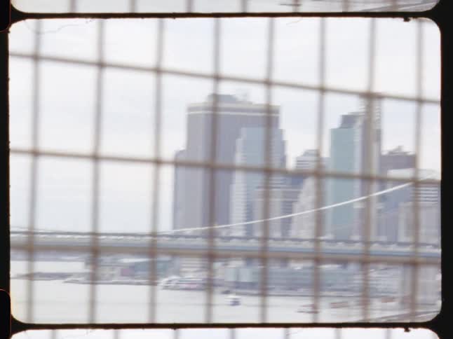 A view from a bridge over a sea of a big city with tall buildings and a quadrangular grid in front