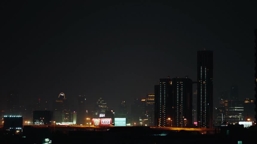A city is shown at night lit up against a foggy black sky