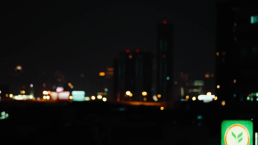 A dark cityscape at night with glowing buildings and advertisements