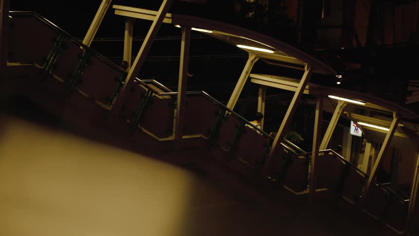 A group of people walking down a staircase at night with light from the ceiling above the stairs reflecting on them