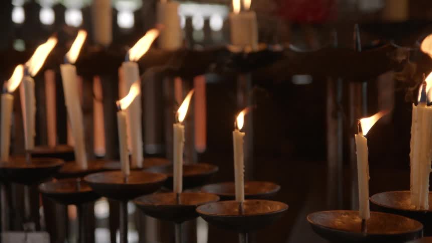 The wind blows the flames of many lit candles