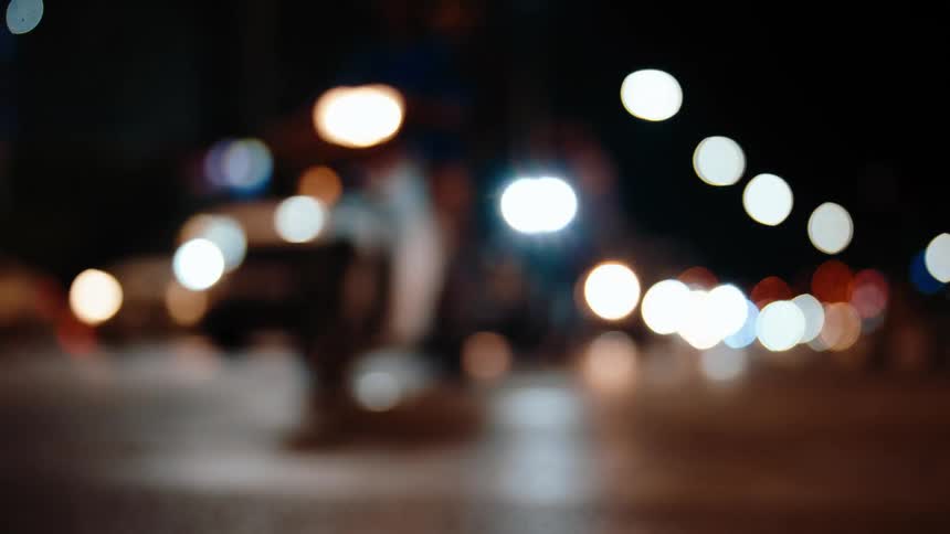 Blurry vehicles drive on a highway at night filling the area with glaring headlights