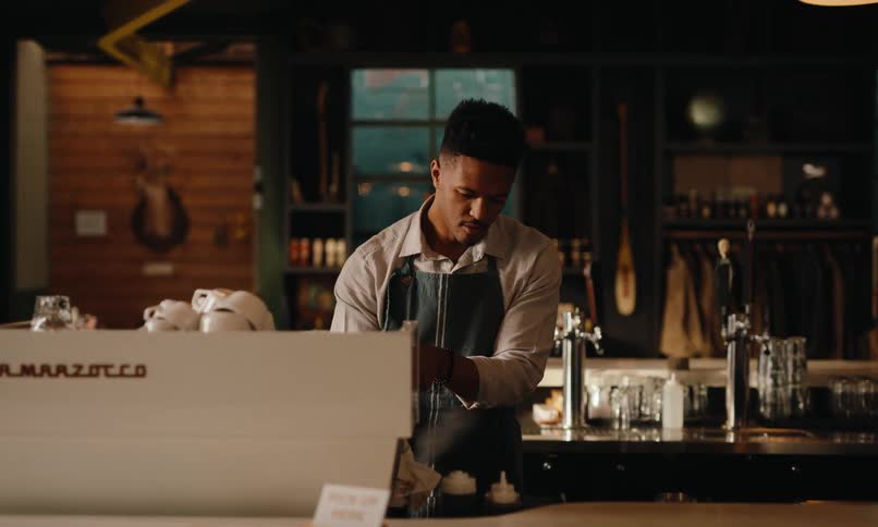 Man behind coffee counter prepares a shot of espresso