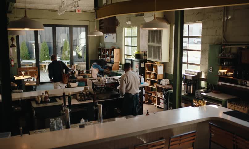 Customer and waiters wearing aprons in a coffee shop
