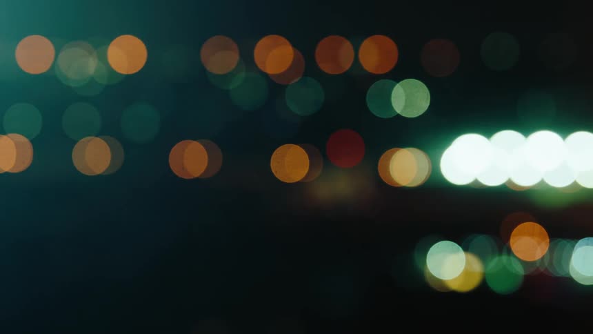 A series of blurry light reflections from cars on the street at night in the city