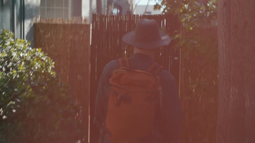 A man walks by trees and a building