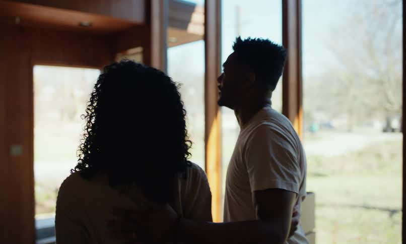Couple hugs while looking around their new house
