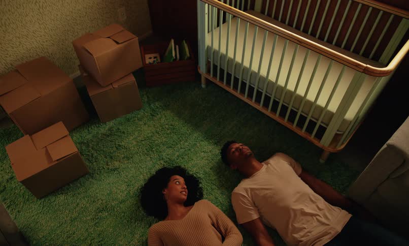 Expecting parents lay on the floor by the crib