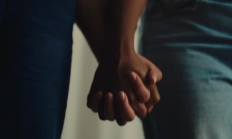 The hands of two people who are intertwining and holding tightly to each other